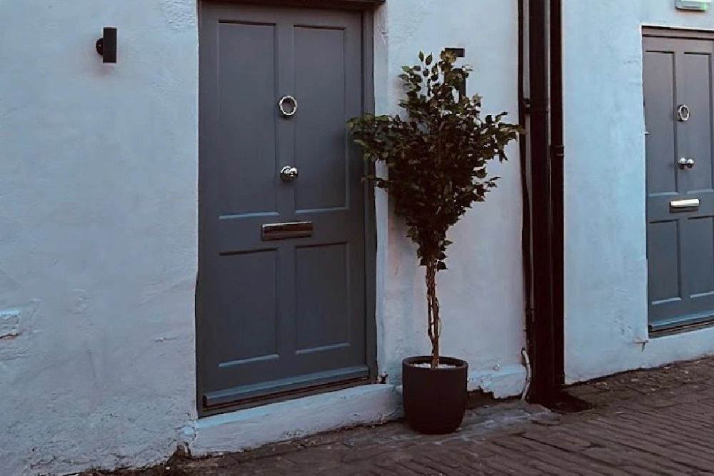 Grey unit door and planted tree in the restored courtyard